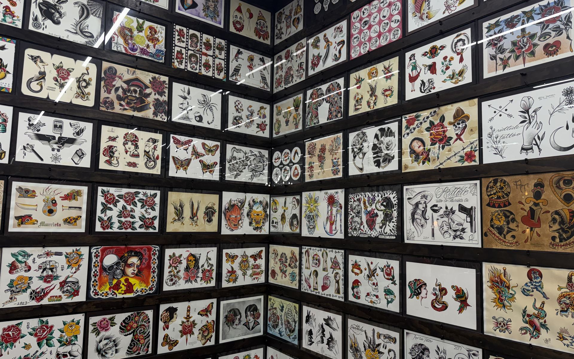 A corner of the Red Tide Tattoo shop covered floor to ceiling in framed traditional tattoo flash